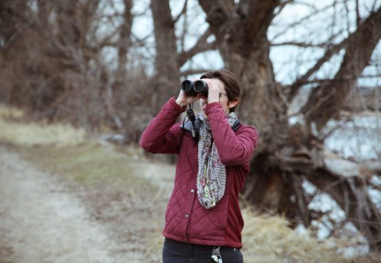 A woman with binoculars searcing for birds on an early winter day. 