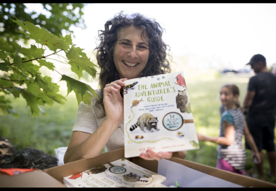Susie Spikol holding a copy of her book, The Animal Adventurer's Guide. 