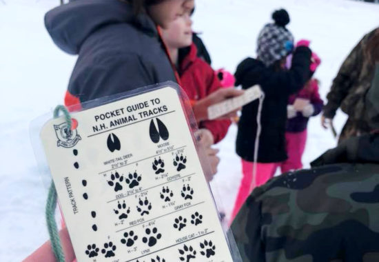 NH Pocket Guide held in the hands of a child outside in the winter.